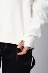 Buzo tipo canguro de corte oversize, color blanco, con capucha y cordones ajustables. Presenta un pequeño estampado de una rosa roja en el pecho y un bolsillo frontal tipo canguro.