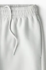 Short de felpa interlock, color gris claro, con cintura elástica con cordón oculto, bolsillos laterales y corte relajado.