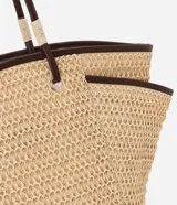 Bolso de playa tipo tote de paja natural con asas de cuero sintético marrón, forro interior y bolsillo interno.