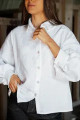 Camisa de lino de corte relajado y silueta holgada, con cuello clásico y cierre frontal de botones forrados en lino a rayas. Presenta mangas largas con puños amplios.