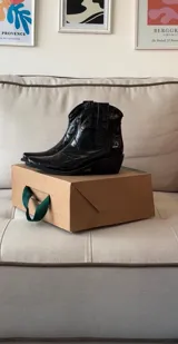 Bota corta estilo texana de charol negro, con punta fina y taco cuadrado bajo.
