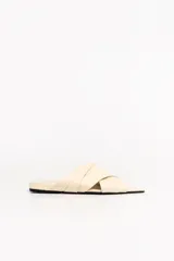Sandalias chatas de cuero de oveja color marfil, con tiras plisadas cruzadas en la parte superior y diseño destalonado.