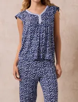 Conjunto de pijama marca René Rofé, compuesto por remera de mangas cortas con escote en V abotonado y pantalón capri con cintura elastizada. Diseño estampado con flores azules sobre fondo blanco.