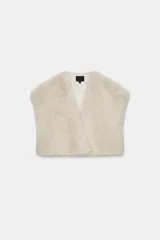 Chaleco Zara de pelo sintético en color beige, con diseño abierto, manga muy corta y cierre lateral con clip.
