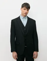 Ambo negro de corte clásico para hombre, compuesto por saco de solapas de muesca con dos botones, chaleco abotonado a juego y pantalón de vestir de corte recto.