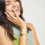 Pulsera ajustable de cordón blanco con un dije central de corazón martillado con baño de plata de ley.