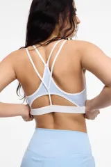 Top deportivo de microfibra en color beige con detalles de ribetes y banda inferior en color marrón. Presenta diseño de espalda estilo nadadora y logo de la marca estampado en la banda elástica inferior.