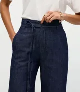 Pantalón de jean corte wide leg en color azul oscuro, con cintura alta, cierre frontal con botón y cremallera, y cinturón de lazo del mismo tejido.