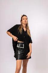 Camisa oversize de manga corta, color negro, con cuello mao y cierre frontal de botones dorados.