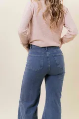 Pantalón de jean estilo wide leg, color celeste claro, con tiro medio, cinco bolsillos y cierre frontal con botón y cremallera.