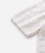 Camisa polo de manga corta con diseño de tejido calado tipo crochet y textura de rombos. Presenta cuello polo clásico y terminaciones en tejido acanalado.