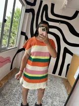 Vestido tejido a rayas horizontales de colores naranja, blanco, rosa, amarillo, verde y crudo, con mangas cortas y terminación con volados.