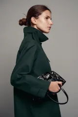 Trench midi ZW Collection verde oscuro con cuello solapa, manga larga, bolsillos laterales en costura y cierre frontal con botones. Cuenta con forro interior a contraste y detalle de solapa corta en el pecho.