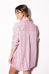 Camisa oversize a rayas celestes y blancas, con cuello camisero, manga larga y hilera de botones dorados metálicos.