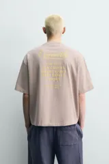 Camiseta boxy fit color gris topo, de cuello redondo y manga corta, con pequeño estampado frontal a contraste.