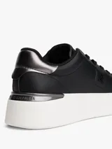 Zapatillas de plataforma Tommy Hilfiger, color negro con suela blanca. Presentan un diseño de corte bajo con cordones, confeccionadas en cuero y material sintético, con el monograma TH en el lateral y detalles metálicos en el talón.