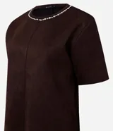 Remera de corte regular confeccionada en gamuza sintética color negro, con mangas cortas y cuello redondo decorado con una aplicación de pedrería brillante.