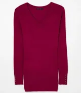 Blusa de punto de corte alargado, color negro, con escote redondo, manga larga y detalle de botones decorativos en los puños.