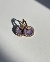 Aros de acero quirúrgico con dije circular de resina rosa y borde de strass dorados.