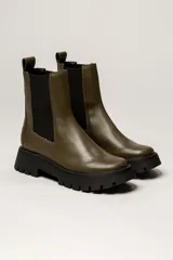 Bota Chelsea color verde militar de cuero, con elásticos laterales negros, tirador trasero y suela track negra.