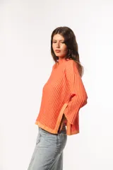 Sweater de punto acanalado color coral, con cuello alto y mangas largas con puños acampanados.
