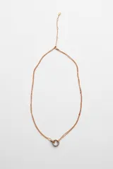 Collar de cadena fina en color cobre, con un dije colgante en forma de aro metálico bicolor que combina tonos plateados y cobrizos.