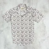 Camisa de manga corta blanca con estampado de flores marrones.