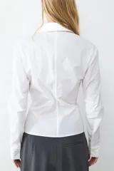 Camisa de popelina negra de manga larga, con cuello clásico y cierre frontal de cremallera con abertura en el bajo.
