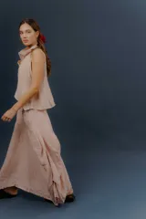 Pollera larga de lino color gris topo, de diseño amplio con volumen, movimiento y bolsillos delanteros. Cuenta con elástico en la cintura y detalles de pinzas y sobretelas en los laterales.