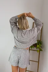 Conjunto de dos piezas en color crema, compuesto por un buzo de cuello alto, mangas largas abullonadas y ajuste en la cintura, junto con un short de tiro alto con terminaciones al corte.