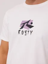 Remera blanca de algodón con estampado gráfico en la espalda. El diseño presenta el logo de Rusty en negro sobre un fondo rectangular lila, con tipografía angular.