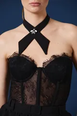 Top tipo corset de encaje negro con escote strapless y copas estructuradas. Presenta detalles de encaje con bordes festoneados y paneles transparentes en el torso.