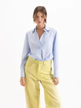 Camisa de poplín de tencel de silueta recta y calce holgado, con diseño a rayas celestes y verdes, cuello camisero con remaches en forma de corazón en las puntas, bolsillo frontal en el pecho y mangas largas con puños anchos.