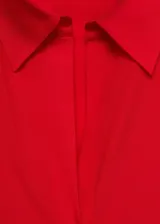 Camisa de corte recto confeccionada en tejido fluido de lyocell, con cuello camisero, cierre frontal de botones, mangas largas con puños abotonados y aberturas laterales en el ruedo.