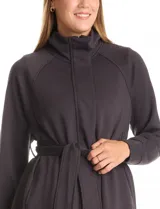 Camperita negra de diseño envolvente, confeccionada en mezcla de poliéster, rayón y elastano. Presenta cuello alto, mangas raglán, cierre frontal con solapa y botones a presión, y un lazo ajustable en la cintura del mismo tejido.