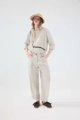 Pantalón de lino color beige de tiro medio, con fit barrel y piernas amplias de silueta relajada. Cuenta con bolsillos delanteros y traseros.