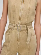 Mono largo de denim azul con corte holgado, recto en las piernas y entallado en el tronco. Tiene cuello camisero, cierre frontal con cremallera y cinturón ajustable.