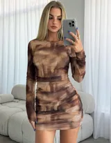 Vestido corto de manga larga con diseño ajustado y fruncido lateral. Presenta un estampado abstracto en tonos marrones y beige con efecto de malla semitransparente.