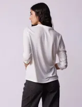 Blusa azul con cuello a la base y escote en V. Tiene bolsillos con cierre metálico.