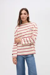 Remera de manga larga con diseño a rayas horizontales en color crema y rojo. Presenta un corte holgado, cuello redondo y un pequeño bordado en el pecho.