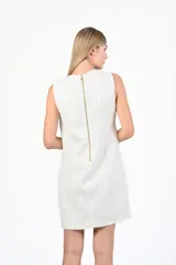 Vestido corto color blanco con hilos dorados, sin mangas y corte recto.