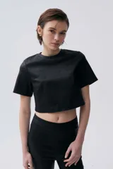 Top corto negro de viscosa, poliamida y elastano, con cuello redondo y mangas cortas.