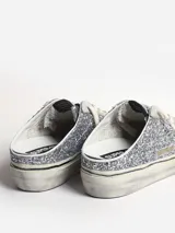 Zapatilla slip-on con glitter plateado, estrella de cuero negro y cordones blancos.
