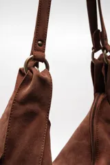Bolso tote de ante suave, de cuerpo blando estilo hobo, con asa larga para el hombro y cierre superior con cremallera.