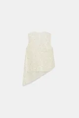 Top sin mangas de cuello redondo, confeccionado en tejido cubierto de lentejuelas brillantes. Presenta un diseño asimétrico en el bajo con una caída lateral pronunciada y cuenta con un forro interior con tirantes finos. Incluye cierre en la espalda con abertura y botón oculto.