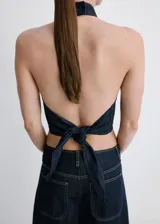 Top crop entallado de tejido de mezclilla, con cuello halter, diseño sin mangas, cierre de botón en el cuello y nudo en la parte posterior.