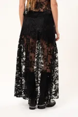 Pollera larga de encaje negro con silueta fluida y diseño asimétrico. Presenta un forro interno hasta la altura del frunce, dejando la parte inferior con transparencias que aportan movimiento.