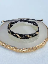 Pulsera tejida a mano con cuentas Miyuki en tonos negro, dorado y plateado.