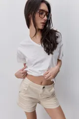 Short de tiro medio y calce ajustado, color blanco, con dobladillos en las piernas y cierre frontal con botón.