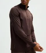 Remera deportiva térmica de manga larga, color marrón, con cuello alto y cierre frontal parcial. Presenta mangas raglán y diseño con recortes.